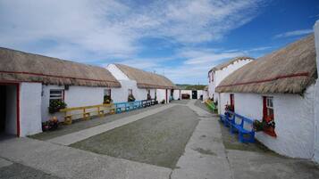 A row of white buildings with thatched roofs and a central pathway.