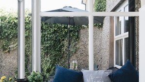 A room with a window seat, a small table with a candle holder, and a potted plant. - Portrush - Hope Cottage - sleeps 5 guests  in 3 bedrooms (Portrush)