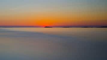 A calm sea at sunset with a distant landmass.