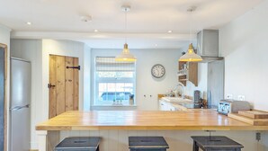 Een moderne keuken met houten barstoelen, hanglampen en een groot eiland.