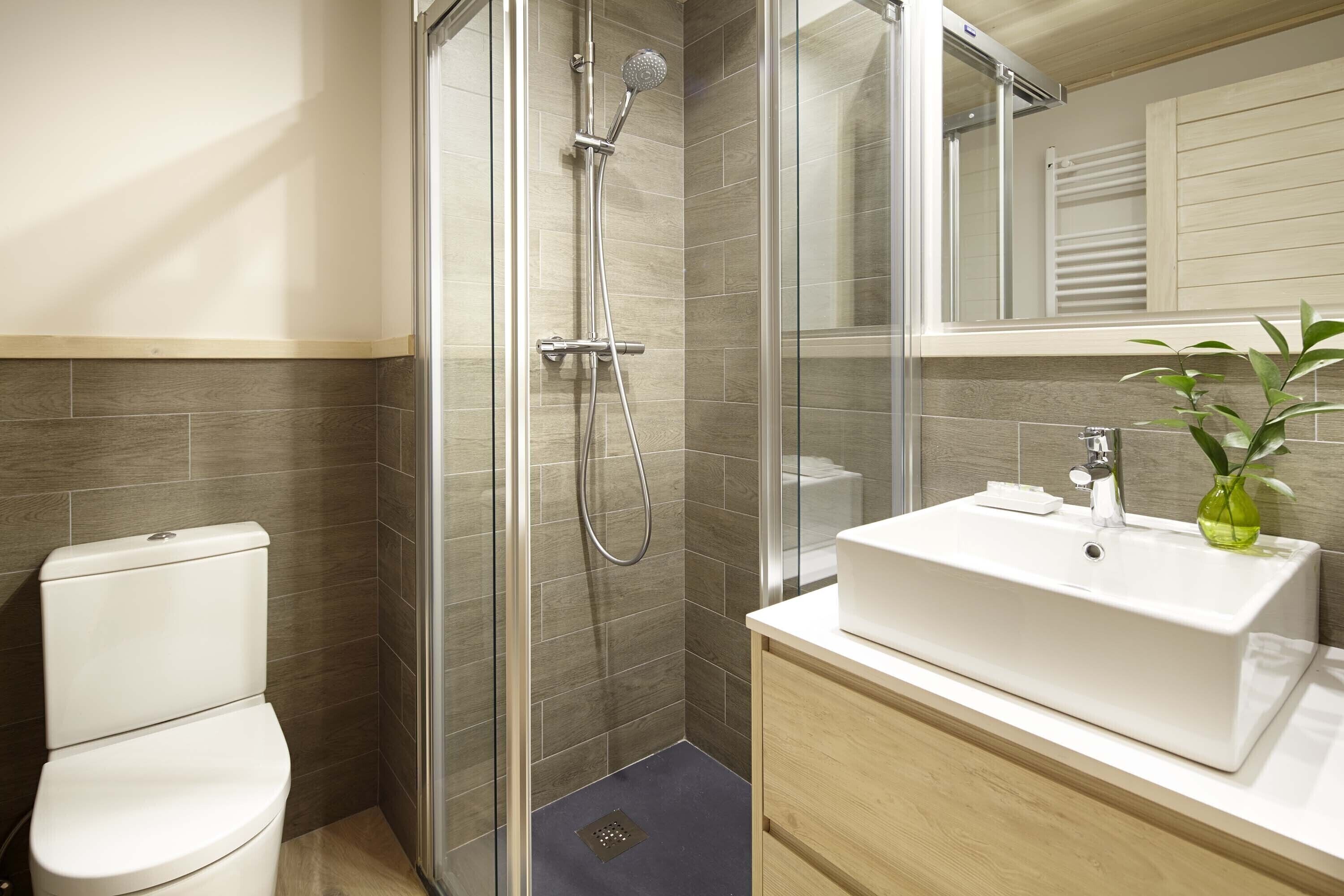 A modern bathroom with a glass-enclosed shower, a white sink, and a toilet.