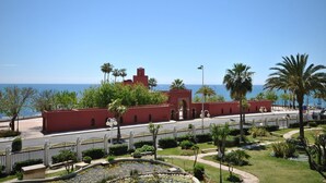 Vista costera con un edificio rojo, palmeras y cielo despejado.