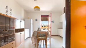 A kitchen with a dining table, chairs, and a refrigerator. - Appartamento Oasi by BarbarHouse (Torre Pali)