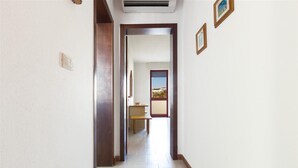 A hallway with a wooden door leading to a room with a window. - Appartamento Oasi by BarbarHouse (Torre Pali)