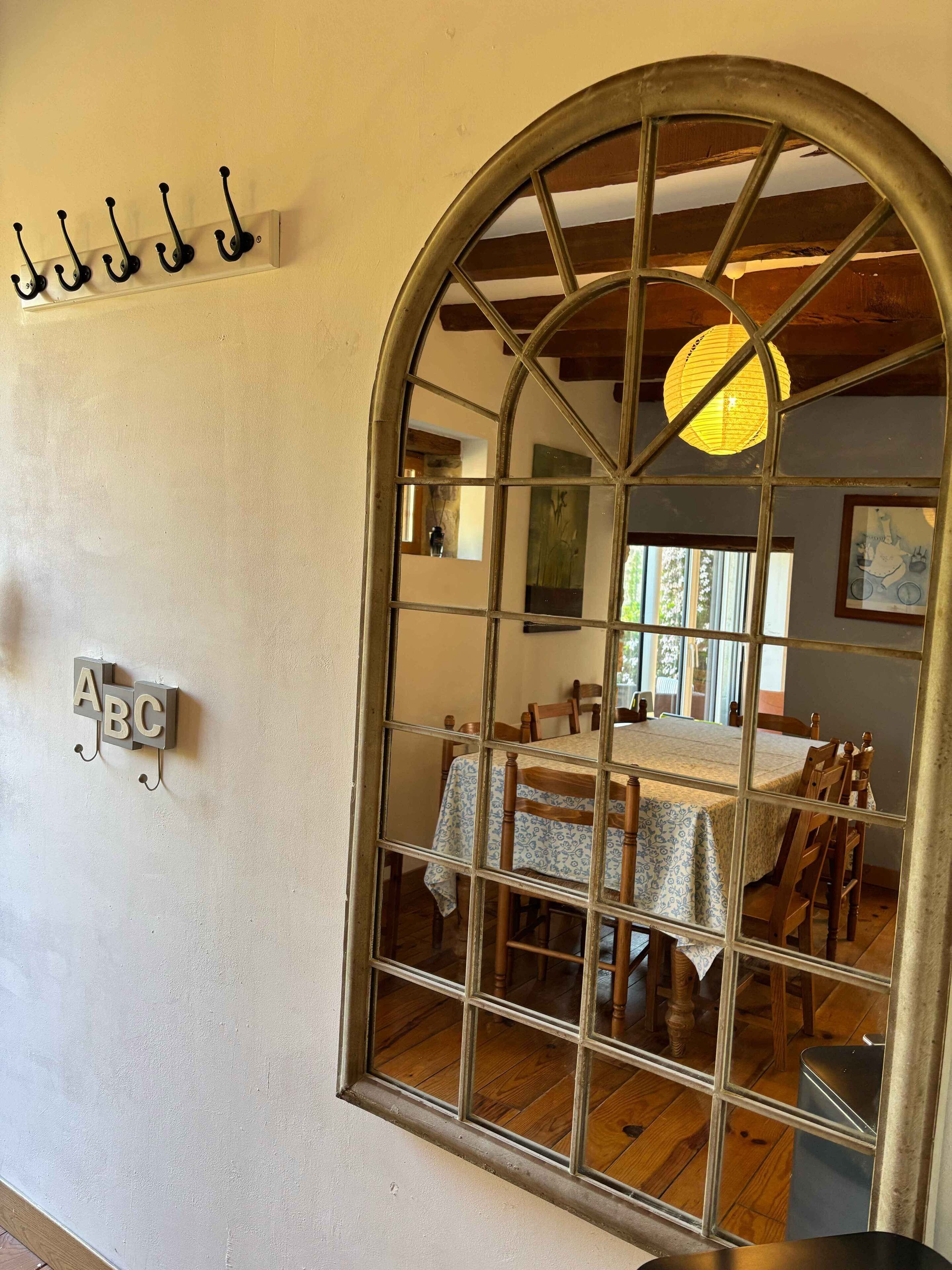 Un coin repas agrémenté d’une grande fenêtre en arc de cercle, de meubles en bois et d’une table recouverte d’une nappe à motifs.