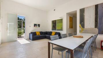 A modern living room with a sectional sofa, a dining table, and a large abstract painting.