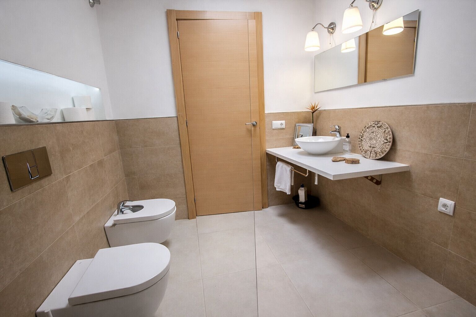 A modern bathroom with a toilet, sink, and mirror.