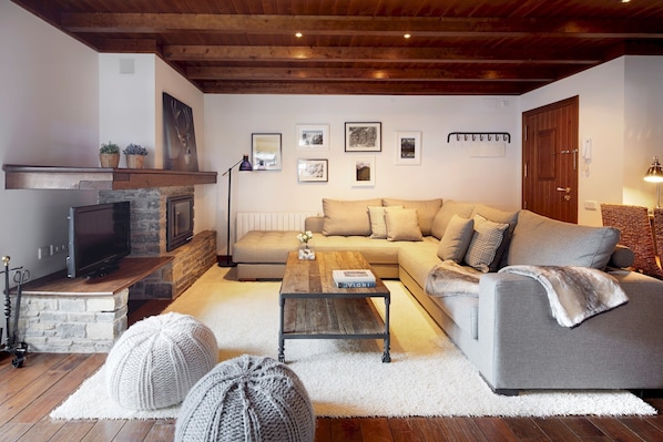 A cozy living room with a fireplace, a sofa, a coffee table, and a television.