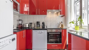 Une cuisine moderne avec des meubles de rangement rouges, un lave-vaisselle, un four et une machine à café.