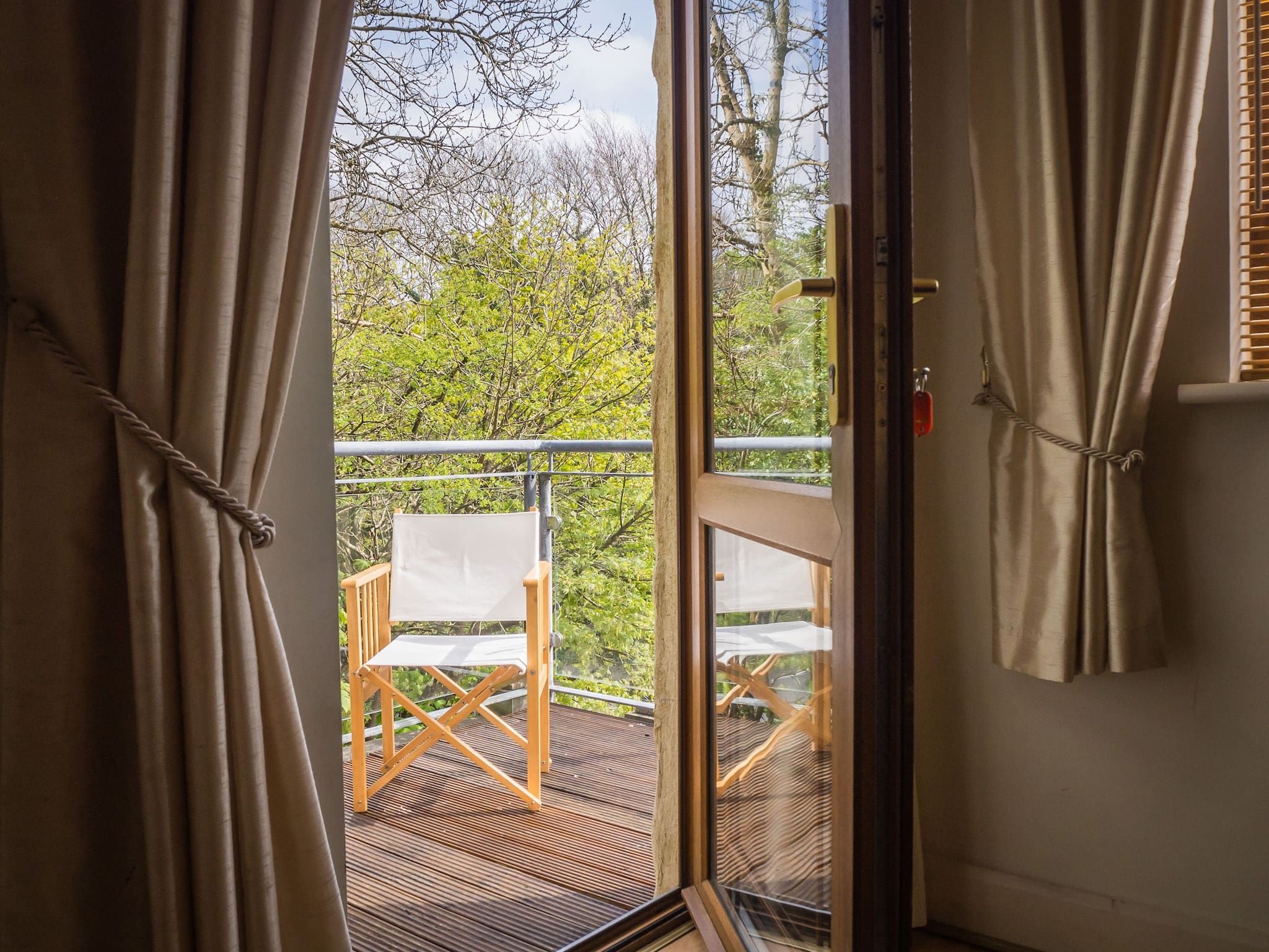 A room with a sliding glass door leading to an outdoor deck with a wooden chair.