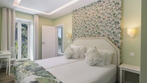 A hotel room with a large bed, a desk, and a view of the outdoors. - 1-bed Superior Apt B2 in character Babosas Village (Funchal)