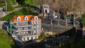 A multi-story hotel with balconies, a parking area, and a stone wall. - 1-bed Superior Apt B2 in character Babosas Village (Funchal)