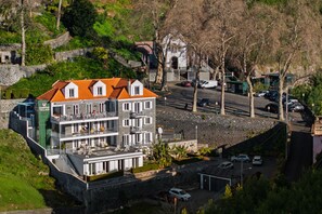 Un hôtel à plusieurs étages doté de balcons, d’un parking et d’un mur en pierre.