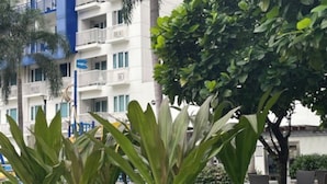Un immeuble à plusieurs étages doté de balcons, entouré d’une végétation luxuriante et d’une pelouse bien entretenue.