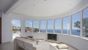 Un salon spacieux avec une grande télévision, un canapé et une vue sur la mer.