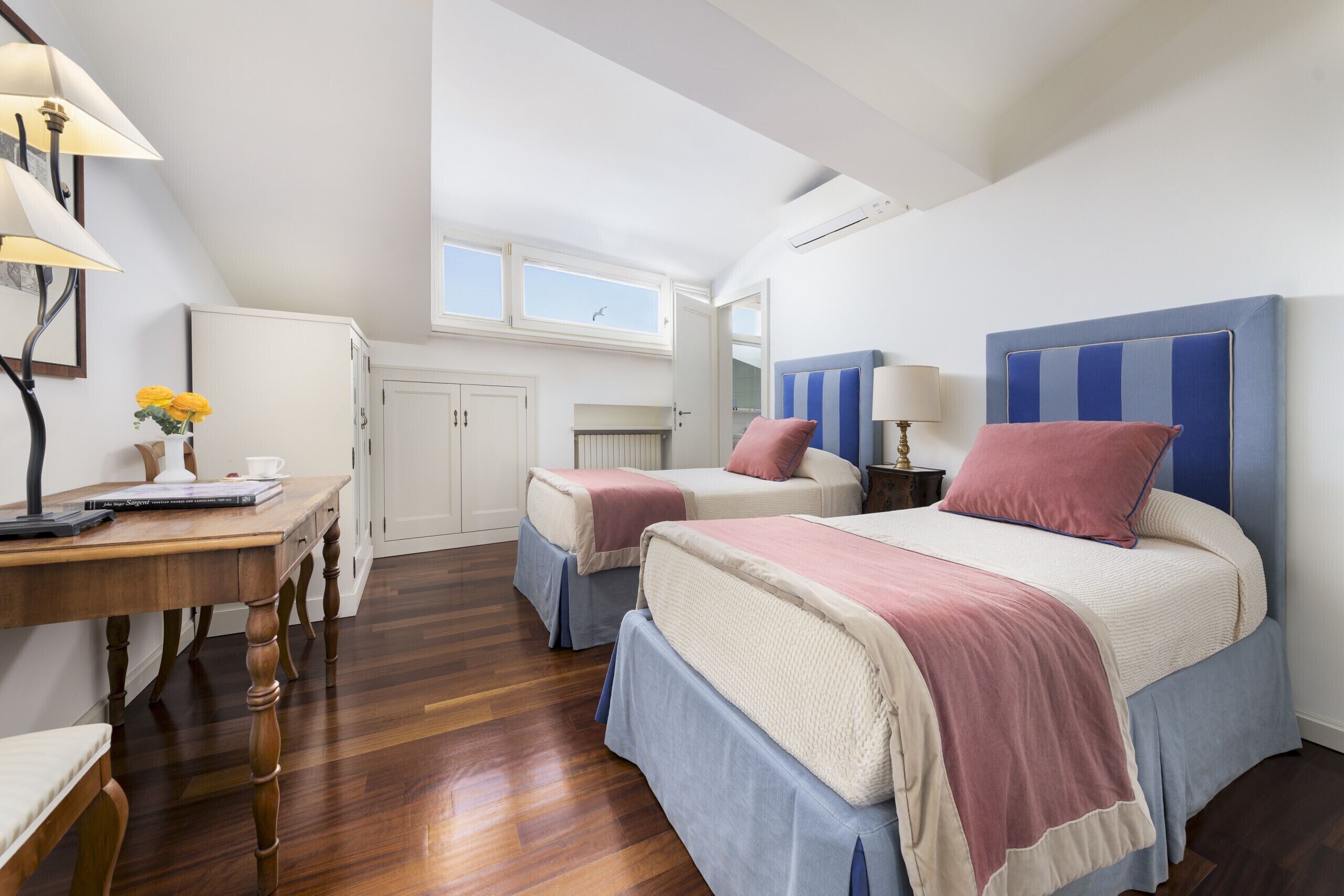 Une chambre avec deux lits, un bureau et une fenêtre.