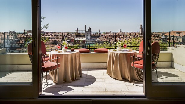 A terrace with two tables and chairs, a view of a cityscape with buildings and a tower, and a clear sky. - Ca' Cerchieri Terrace Canal View (Venice)