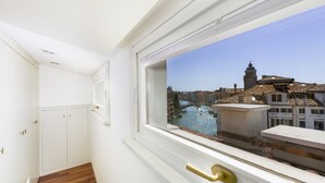 A room with a view of a canal and historic buildings, a wooden floor, and white walls. - Ca' Cerchieri Terrace Canal View (Venice)