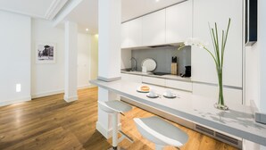 A modern kitchen with white cabinets, a stainless steel sink, and a bar area with stools.