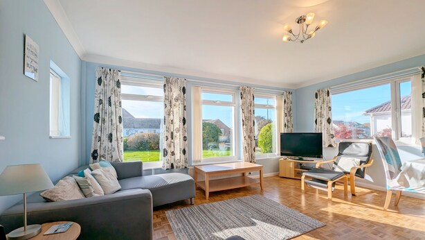 A spacious living room with a sofa, a TV, and a view of the outdoors. - A family house that sleeps 6 guests  in 3 bedrooms (Chichester)