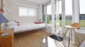A modern bedroom with a single bed, a desk, and a chair. There is a large window providing a view of the outdoors. - A family house that sleeps 6 guests  in 3 bedrooms (Chichester)