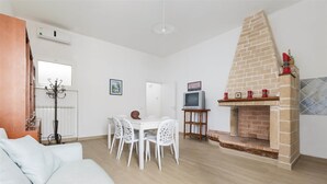 A modern living room with a fireplace, white furniture, and a dining area.