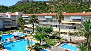 A resort with multiple swimming pools, palm trees, and a mountainous backdrop.