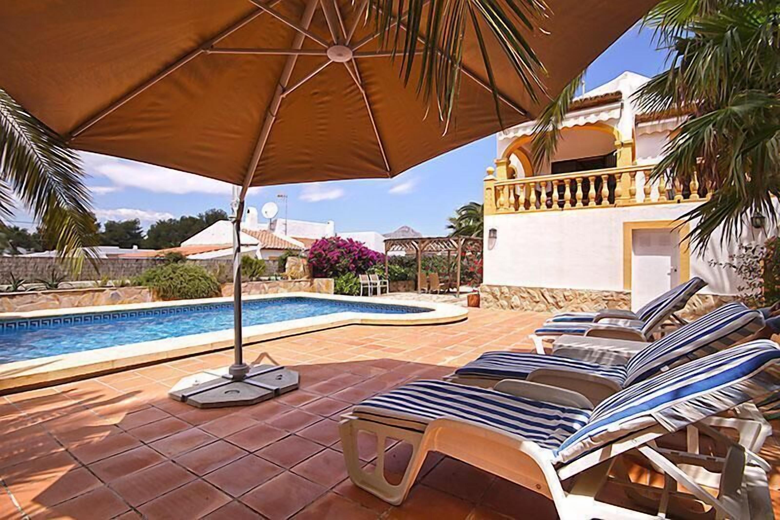 Un área de piscina con sillones de descanso y un parasol grande.