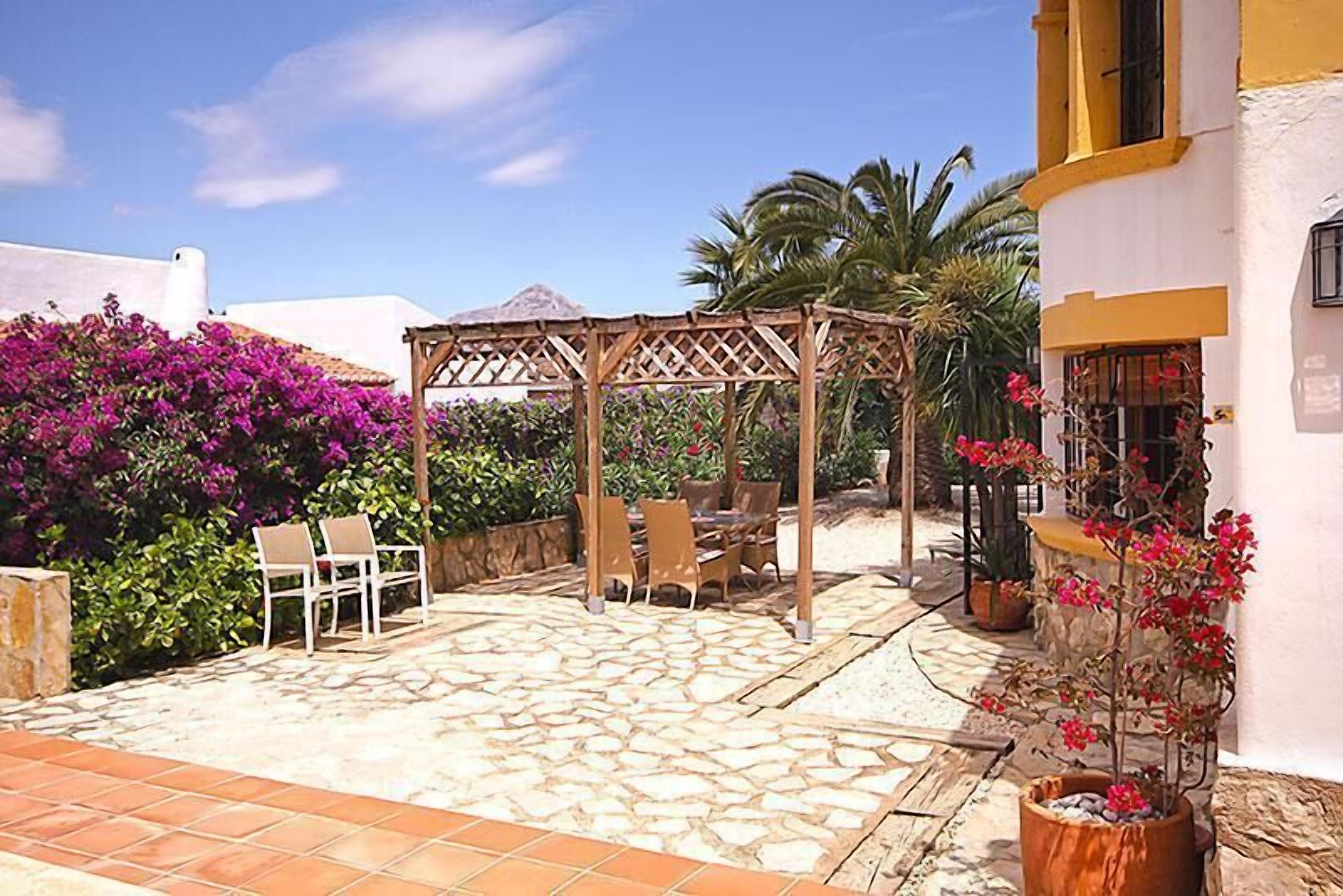 A patio with stone flooring, a wooden pergola, and outdoor furniture.