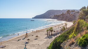 Ein Strand mit einem Rettungsturm, Sonnenschirmen und Palmen.