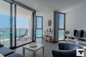 A modern living room with a balcony overlooking the sea, a TV, and a bookshelf. - Bernia al Mar 8B - Grupo Turis - Calpe, Costa Blanca (Calpe)
