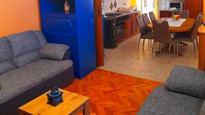 Ett kompakt vardagsrum med en soffa, ett litet träbord och en matplats med stolar och ett bord.
