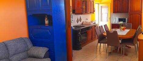 Um espaço de estar compacto com sofá, uma pequena mesa de madeira e um espaço de refeições com cadeiras e mesa.