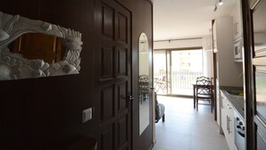 A modern kitchen with a large island, a dining area with chairs, and a sliding glass door leading to a balcony. - JARDINS DEL MAR 130 (Estartit)