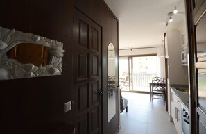 A modern kitchen with a large island, a dining area with chairs, and a sliding glass door leading to a balcony.