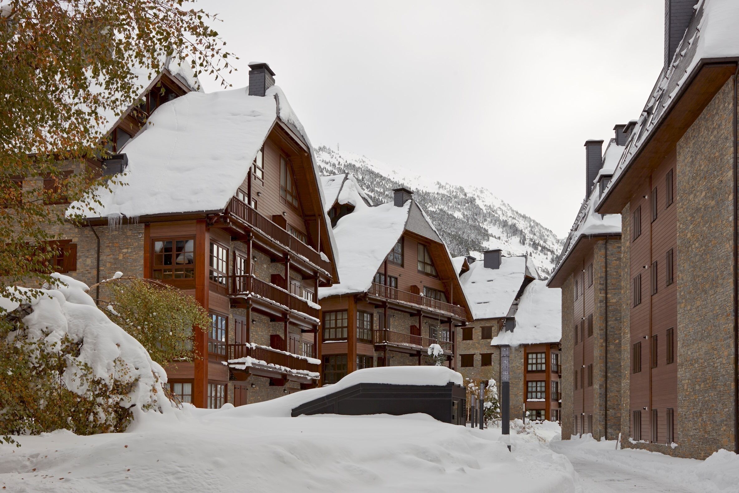 A snow-covered building with multiple balconies and a mountain backdrop.