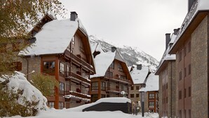 En snötäckt byggnad med flera balkonger och en bergskedja i bakgrunden.
