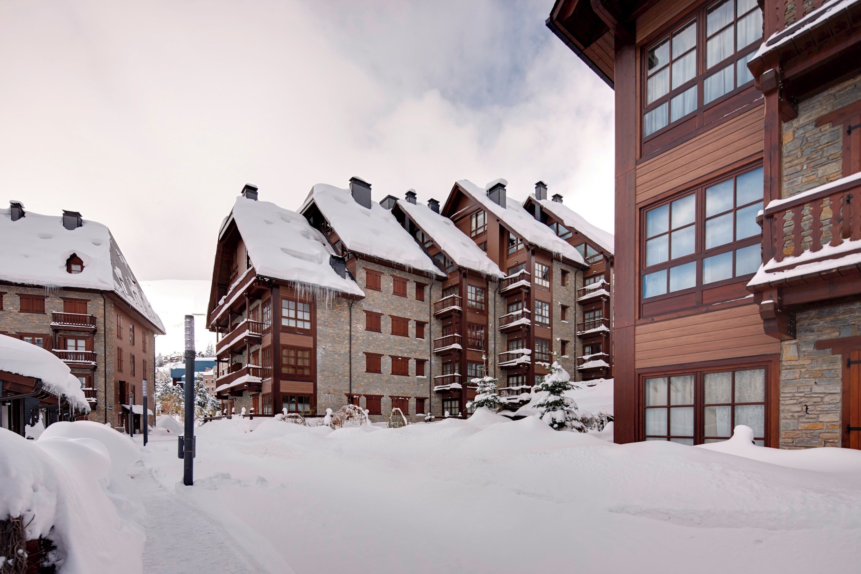 A snow-covered building with multiple balconies and a stone facade.