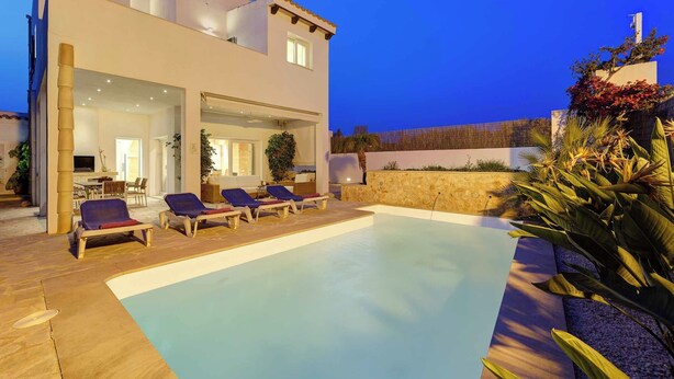 A modern house with a swimming pool, outdoor seating, and a well-maintained garden.