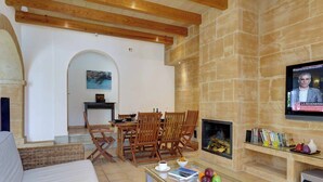 A cozy living room with a stone fireplace, wooden furniture, and a television mounted on the wall.