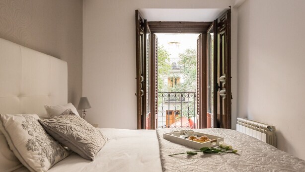 Une chambre à coucher avec un lit, des oreillers, une table de chevet avec une lampe et un plateau contenant des éléments pour le petit-déjeuner.