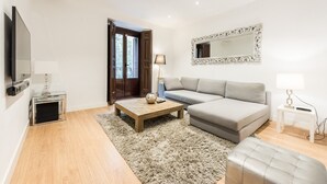 Un salon moderne avec un canapé, une table basse, un téléviseur et une lampe.