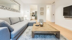 Un salon moderne avec un canapé gris, une table basse en bois et un grand miroir.