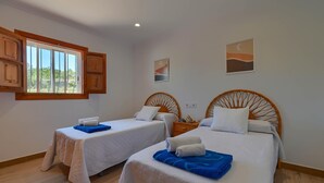 A hotel room with two beds, wooden headboards, a window with wooden shutters, and a small table with a lamp. - Rustic and cheerful holiday home in Javea, Costa Blanca, Spain  with private pool for 6 persons (Javea)