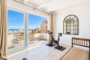 A balcony with a view of the city, an exercise bike, and a wooden bench.