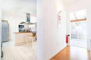 A modern kitchen with white cabinetry, stainless steel appliances, and a wooden dining table.
