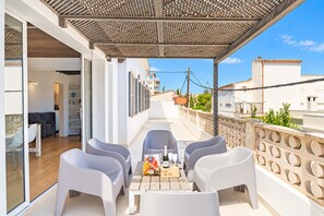 A balcony with white plastic chairs and a table, a bottle of wine, and glasses on the table. - VILLA OASIS TERRA BLANCA (Palma de Mallorca)