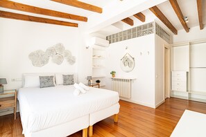 Une chambre moderne avec un grand lit, des poutres en bois, un radiateur et une armoire.