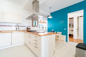 Une cuisine moderne avec des meubles blancs, un plan de travail en bois et un mur d’accent bleu.