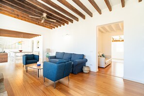 A spacious living room with wooden flooring, a sectional sofa, and a dining area with a table and chairs.